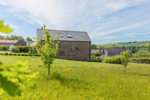 a stone house in a field with trees in the foreground at 3 Bed in Loddiswell oc-t34185 in Churchstow