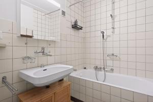a white bathroom with a sink and a bath tub at Bistro Walk Apartment in Lausanne +23 photos