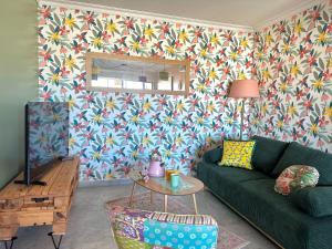 a living room with a green couch and floral wallpaper at Sète en couleurs in Sète