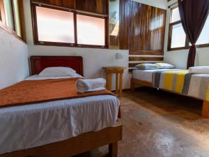 two beds in a room with two windows at Las Barracas de la Barra in Malucano