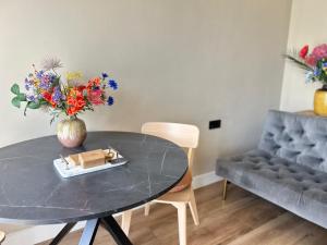 a table with a vase of flowers and a couch at Lovely Spacious Apartment in Zandvoort +10 photos