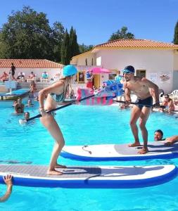 two people on paddle boards in a swimming pool at ZEcamping 4 étoiles avec parc aquatique - sauna et hammam in Sanguinet +7 photos