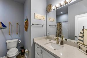 a bathroom with a sink and a toilet and a mirror at Steps to the Beach l Modern Interior in Crystal Beach +56 photos