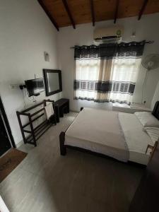 a bedroom with a large bed and a window at Madusanka Holiday Home in Gomagoda