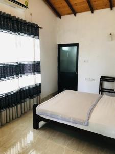 a bed in a room with black doors and windows at Madusanka Holiday Home in Gomagoda
