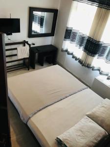 a bedroom with two beds and a desk and windows at Madusanka Holiday Home in Gomagoda