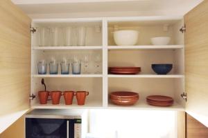 a kitchen pantry with cups and plates and a microwave at Donovaly Kamzík in Donovaly