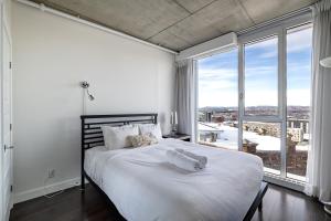 a white bedroom with a large bed and large windows at Les Immeubles Charlevoix - Le 760-415 in Quebec City
