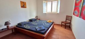 ein Schlafzimmer mit einem Bett mit blauen Laken und einem Stuhl in der Unterkunft APARTMENT SALINAS VILA DO MAIO WiFi FREE in Vila do Maio