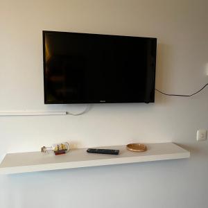 a flat screen tv on a wall with a remote control at Kumpukuja apartment in Kouvola