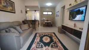 a living room with a couch and a flat screen tv at Casa Mobiliada - Praia Imbassaí in Imbassai