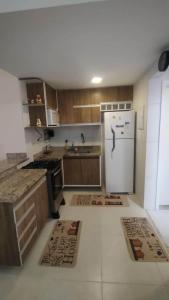 a kitchen with wooden cabinets and a white refrigerator at Casa Mobiliada - Praia Imbassaí in Imbassai