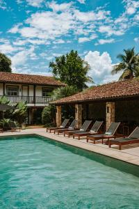a swimming pool with lounge chairs next to a house at Pousada Literária de Paraty in Paraty