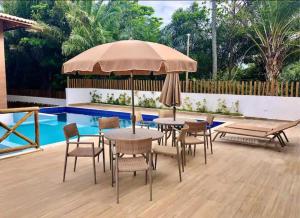 a table and chairs with an umbrella next to a pool at Casa Mobiliada - Praia Imbassaí in Imbassai