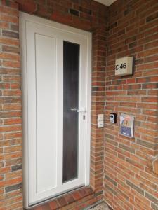 a white door on a brick wall with a sign at Ferienwohnung Seesternchen am Deich2 C46 in Norden