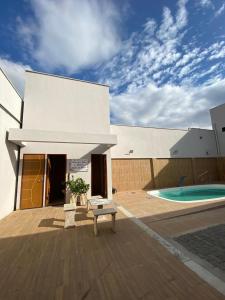 a white building with a bench in front of a pool at Chácara Julião da usina in Juazeiro do Norte