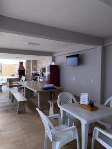 a dining room with tables and chairs and a flat screen tv at Chácara Julião da usina in Juazeiro do Norte