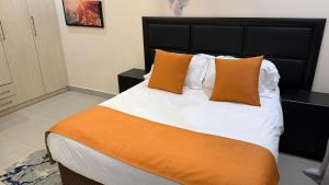 a bedroom with a large bed with orange and white pillows at Artem Apartments - Apartment 1 in Kitwe +14 photos