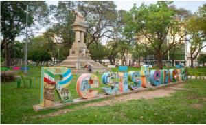 a sign in a park with a statue in the background at Monoambiente zona UNNE in Resistencia