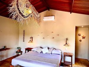 a bedroom with a bed and a chandelier at Chalé Caju Knots in Parajuru