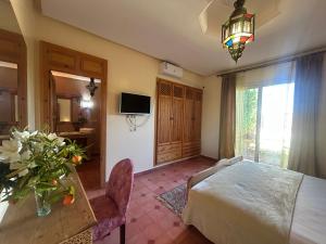 a bedroom with a bed and a table and a television at Private pool villa & garden Marrakech in Marrakesh
