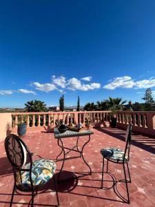 two chairs and a table on a brick patio at Private pool villa & garden Marrakech in Marrakesh