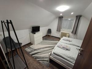 a small bedroom with a bed and a television at Kakukkfészek Apartmanok in Kiskunmajsa