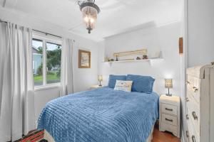 a bedroom with a blue bed and a window at Coho Cottage in Rockaway Beach