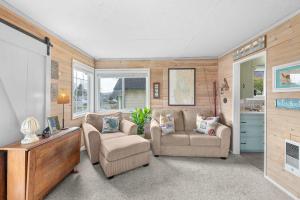 a living room with two chairs and a tv at Coho Cottage in Rockaway Beach