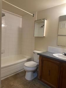 a bathroom with a toilet and a tub and a sink at Your private room CozyVibe in Edmonton