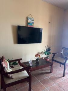 a living room with a table and a tv on a wall at Casa Tradição do Catu in Aquiraz