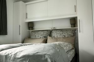 a bed in a bedroom with white walls and white cabinets at Hof Eichendiek Time Out Village- Haus Naturruhe in Blekendorf
