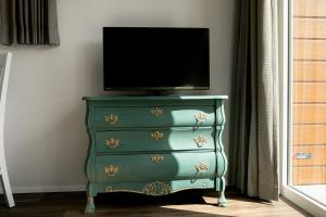a green dresser with a television on top of it at Hof Eichendiek Time Out Village- Haus Naturruhe in Blekendorf