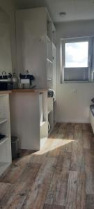 a kitchen with white cabinets and a wooden floor at Surf Shack 3 - Zimmer am Strand, Parkplatz, WLAN, Kiten, Surfen, Chillen im Gemeinschaftsgarten, Naturstrand, Restaurants und Geschäfte in 5 Minuten erreichbar, lockere Atmosphäre in Dahme