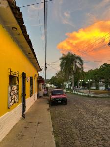 a red car parked next to a yellow building at Hostal El Amate #3 in Suchitoto +6 photos