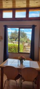 a table with a vase of flowers on it in front of a window at Cabaña Vicente del Mar in Isla Negra