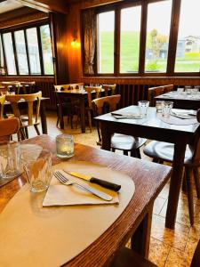 a dining room with tables and chairs and windows at Auberge La Cléa in La Pesse