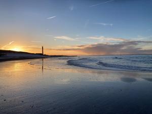 a sandy beach with the ocean and the sunset at PuraVida in Westkapelle