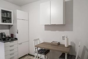 a small kitchen with a small table and white cabinets at Dreiländer-Blick Apartment 2 Schlafzimmer in Lörrach +2 photos