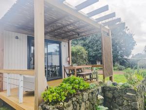 a patio with a stone wall and a pergola at Azor'Oasis in Calhetas