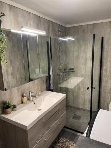 a bathroom with a white sink and a shower at Modern apartment - Balcony, Parking, BBQ in Vossevangen