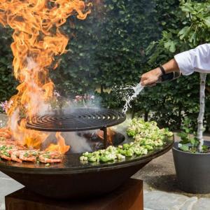 a person is cooking food on a grill with fire at Azor'Oasis in Calhetas