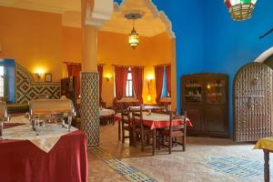 a restaurant with tables and chairs in a room at Hotel Kasbah Azalay in Mhamid