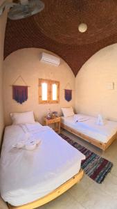 two beds in a room with two windows at Asfay Lodge Siwa in Siwa