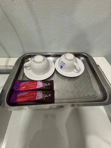 a tray with two cups and plates and a book at KaizaHotel Suvarnabhumi Airport in Lat Krabang
