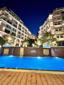 a blue pool in front of buildings at night at La Mer Prime Time in Varna City