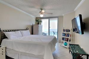 a bedroom with a bed and a television and a balcony at Summerwinds #1203 in Navarre