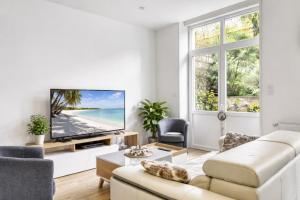 a living room with a white couch and a tv at Au jardin de la Basilique in Boulogne-sur-Mer