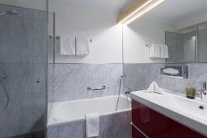 un bagno con vasca, lavandino e doccia di Hotel Nolda a Sankt Moritz Altre 37 foto
