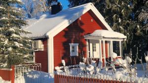 a small red house with snow on the roof at Traditional Log Cabin - Self check-in in Arvidsjaur